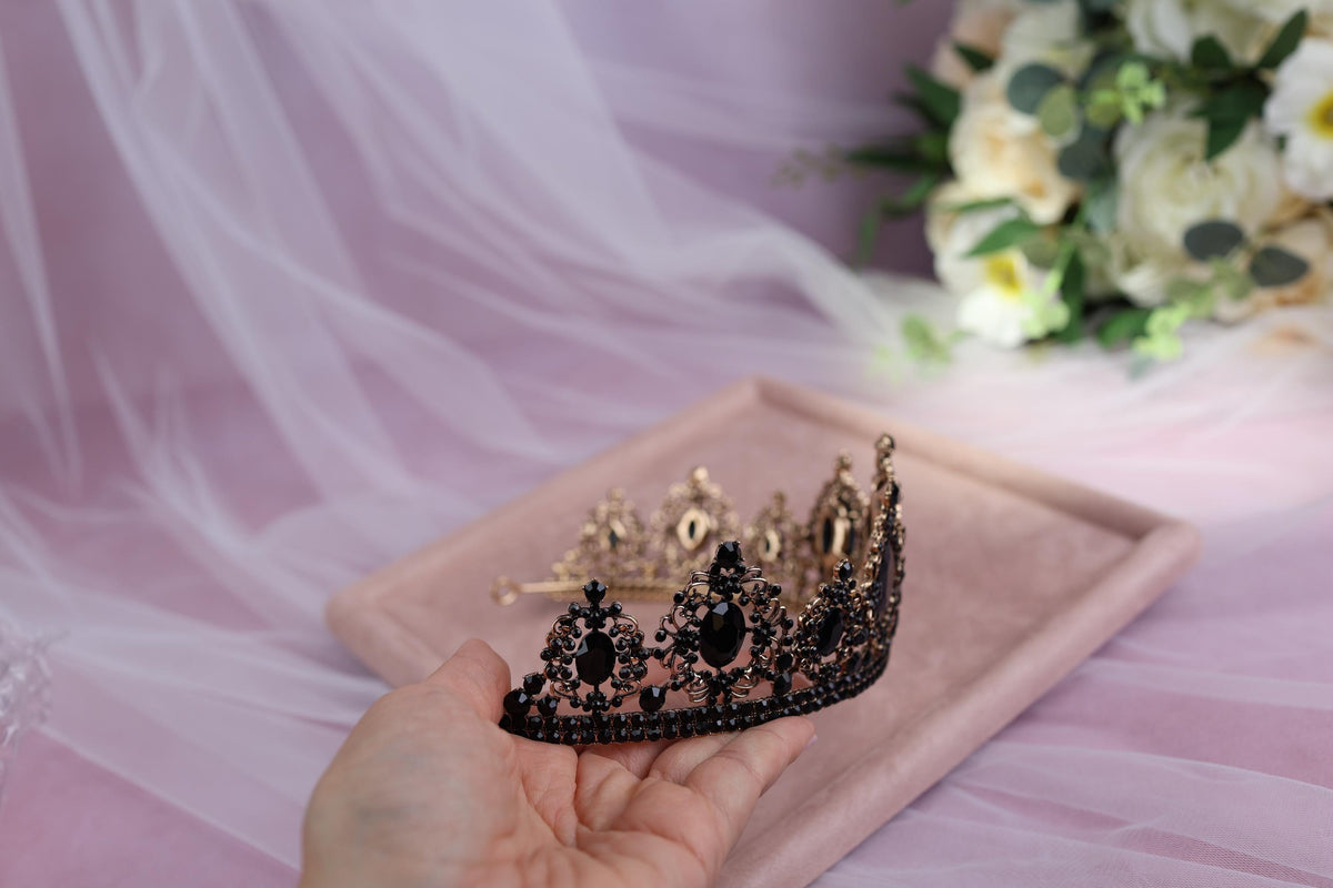 a hand holding a tiara on top of a pink tray