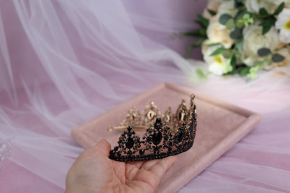 a hand holding a tiara on top of a pink tray