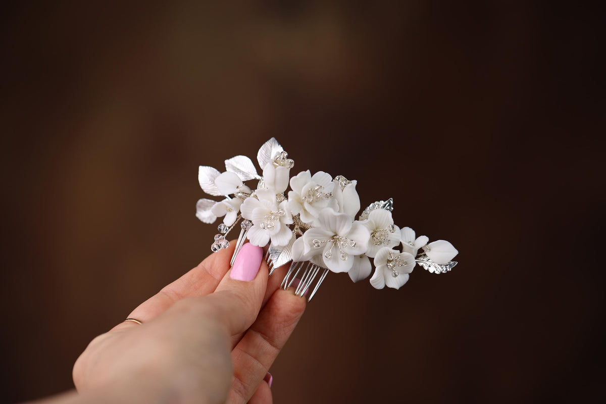 a hand holding a white flower hair comb