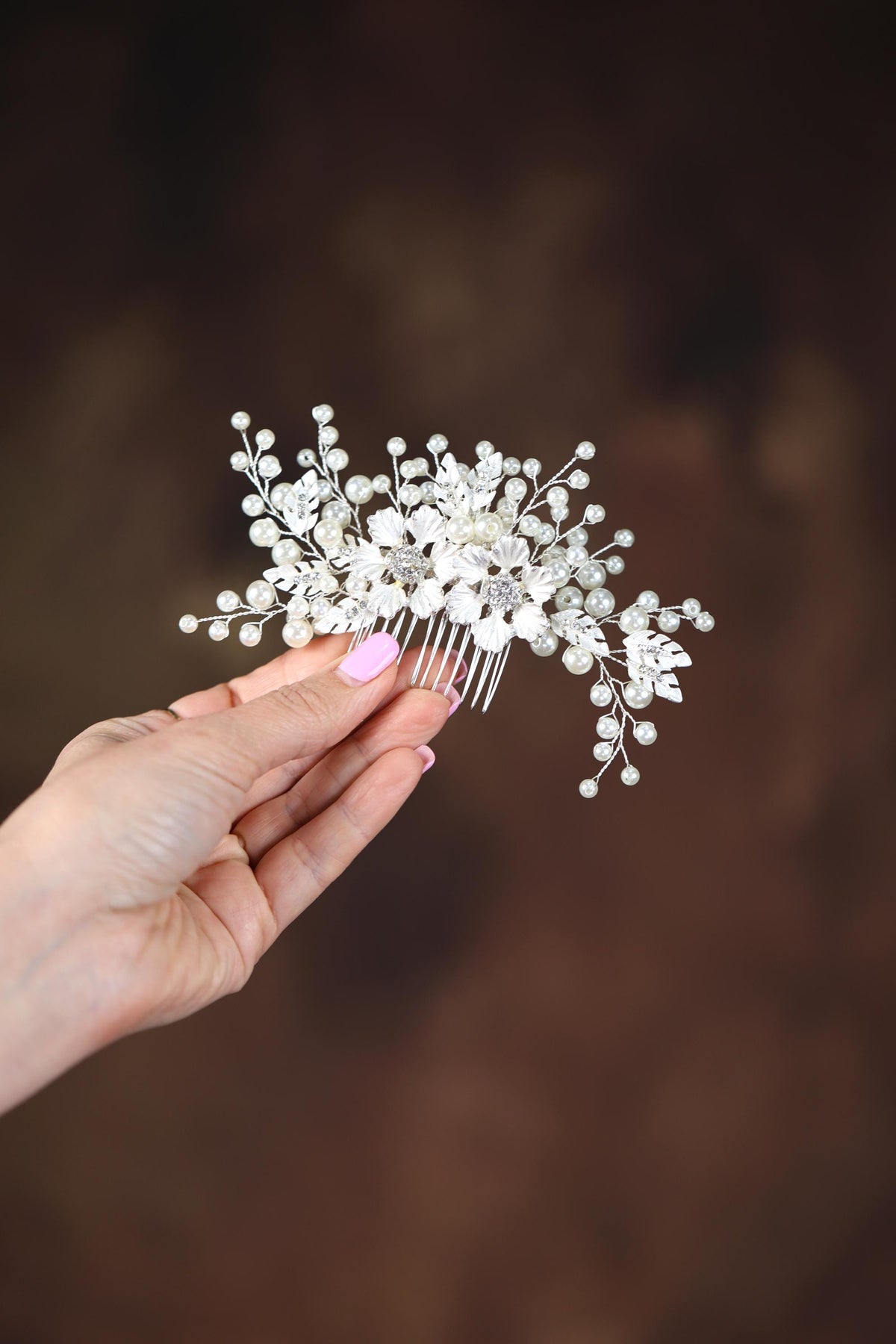 a hand holding a hair comb with white flowers on it