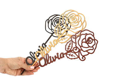 A hand is holding a decorative piece with a floral design, featuring a rose and leaves.