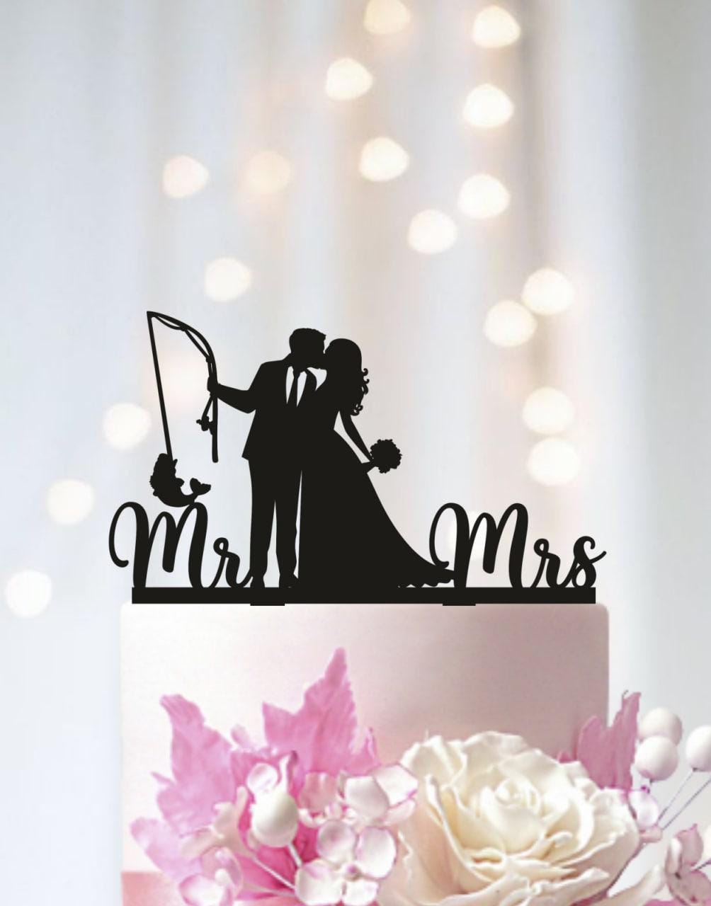 A silhouette of a bride and groom on a wedding cake topper, with the words "Mr. & Mrs." written below them.