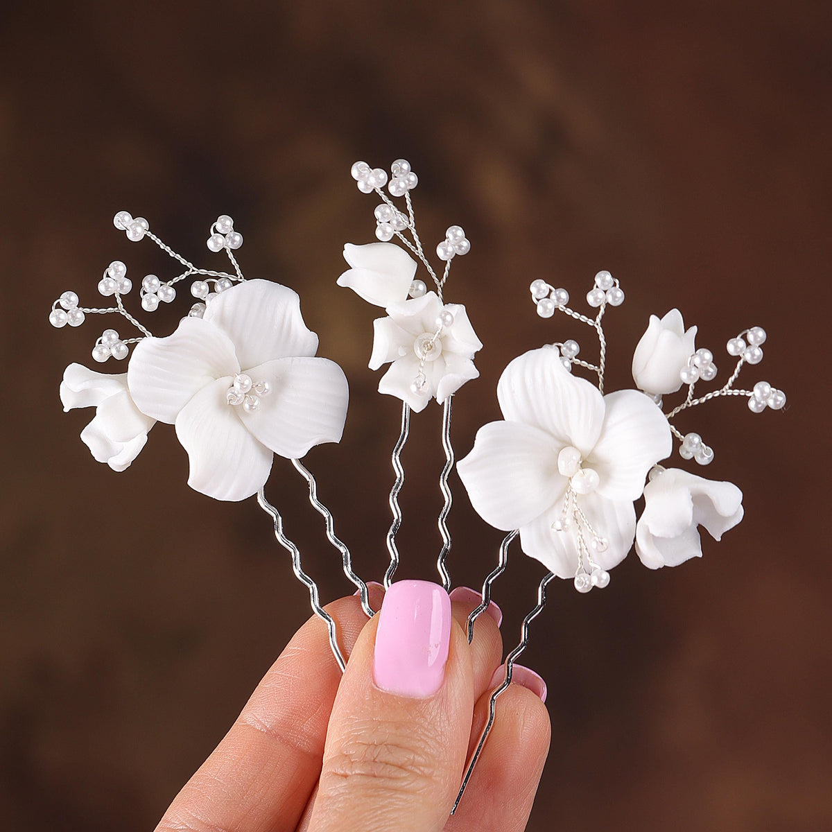 a hand holding a white flower arrangement with pearls