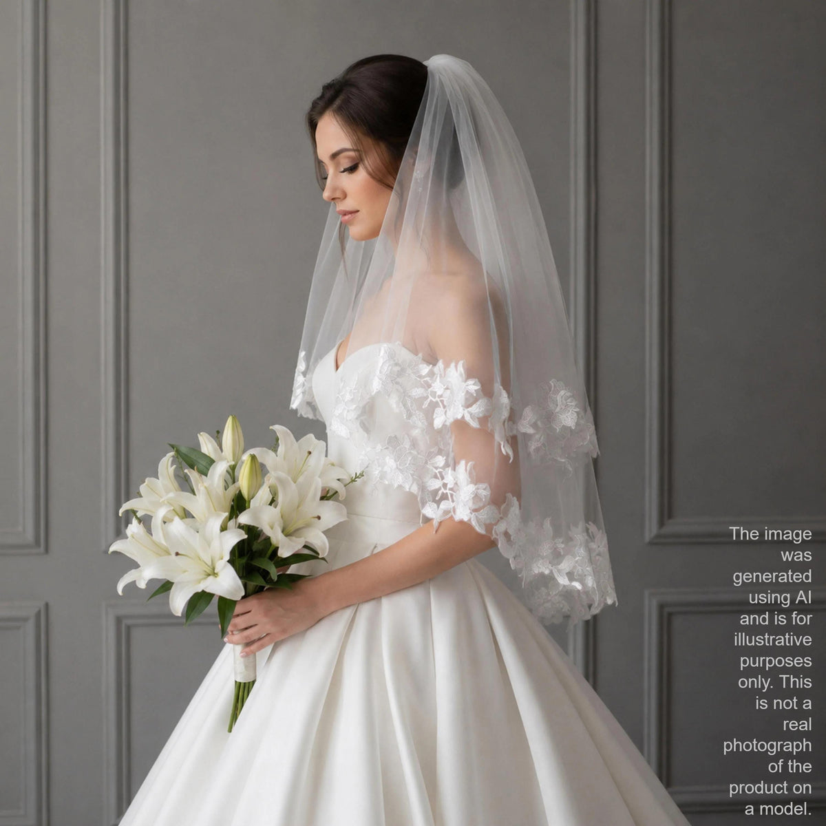 A bride in a white wedding dress holding a bouquet of white lilies stands against a gray wall.