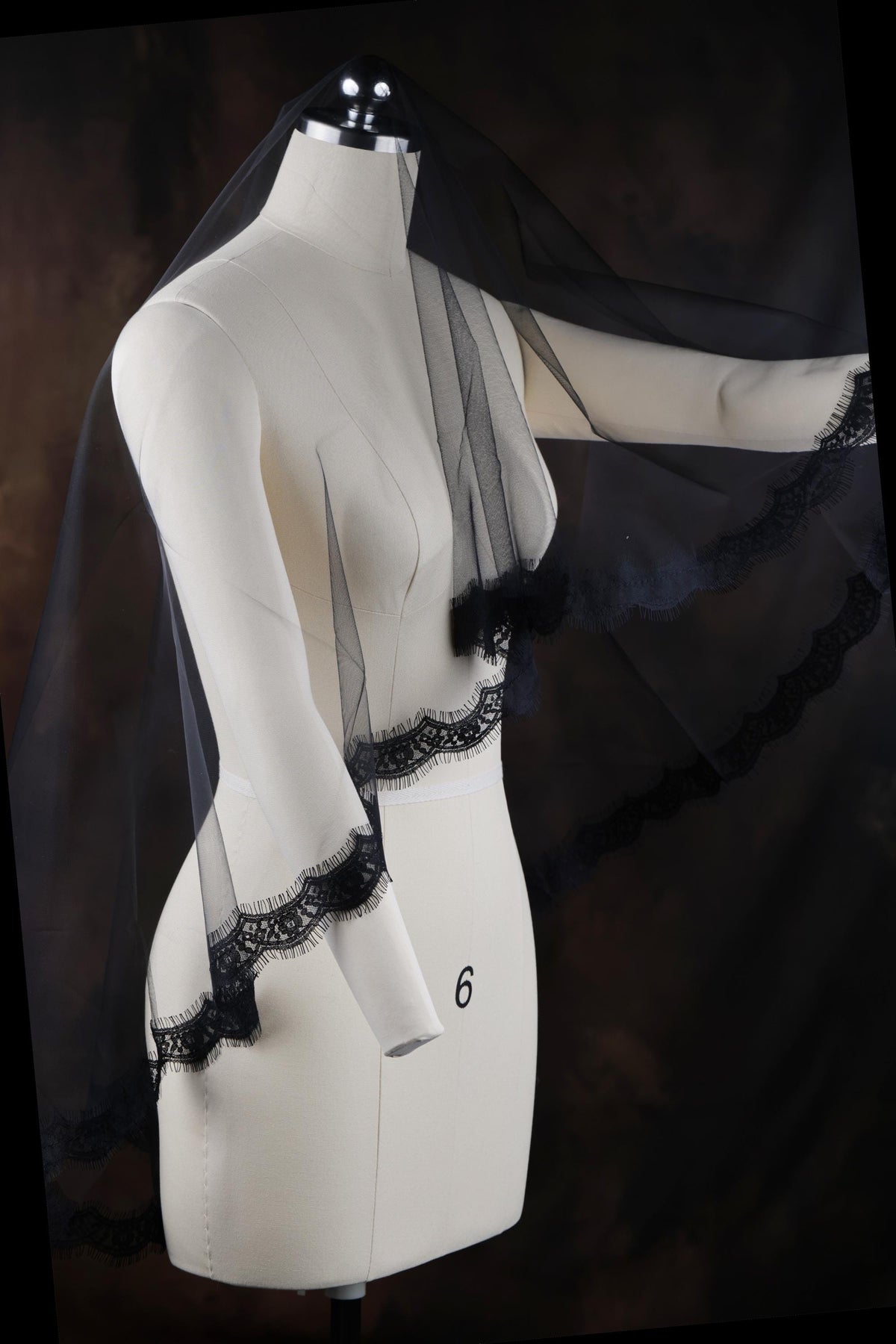 a white mannequin with a black veil on top of it