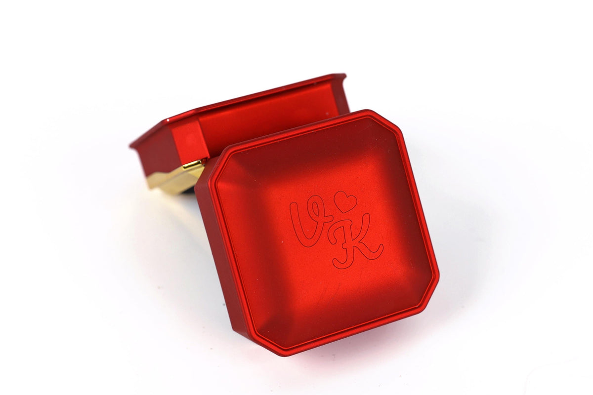 A red metal box with a heart and letter "V" engraved on it.