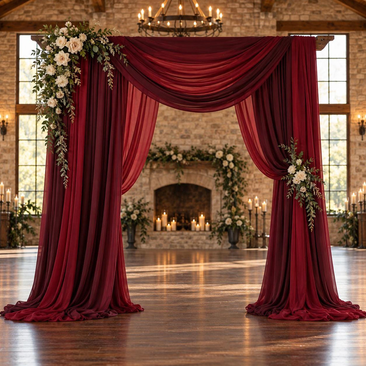 a beautifully decorated wedding arch with red curtains and white flowers, set against a rustic brick wall and a fireplace.