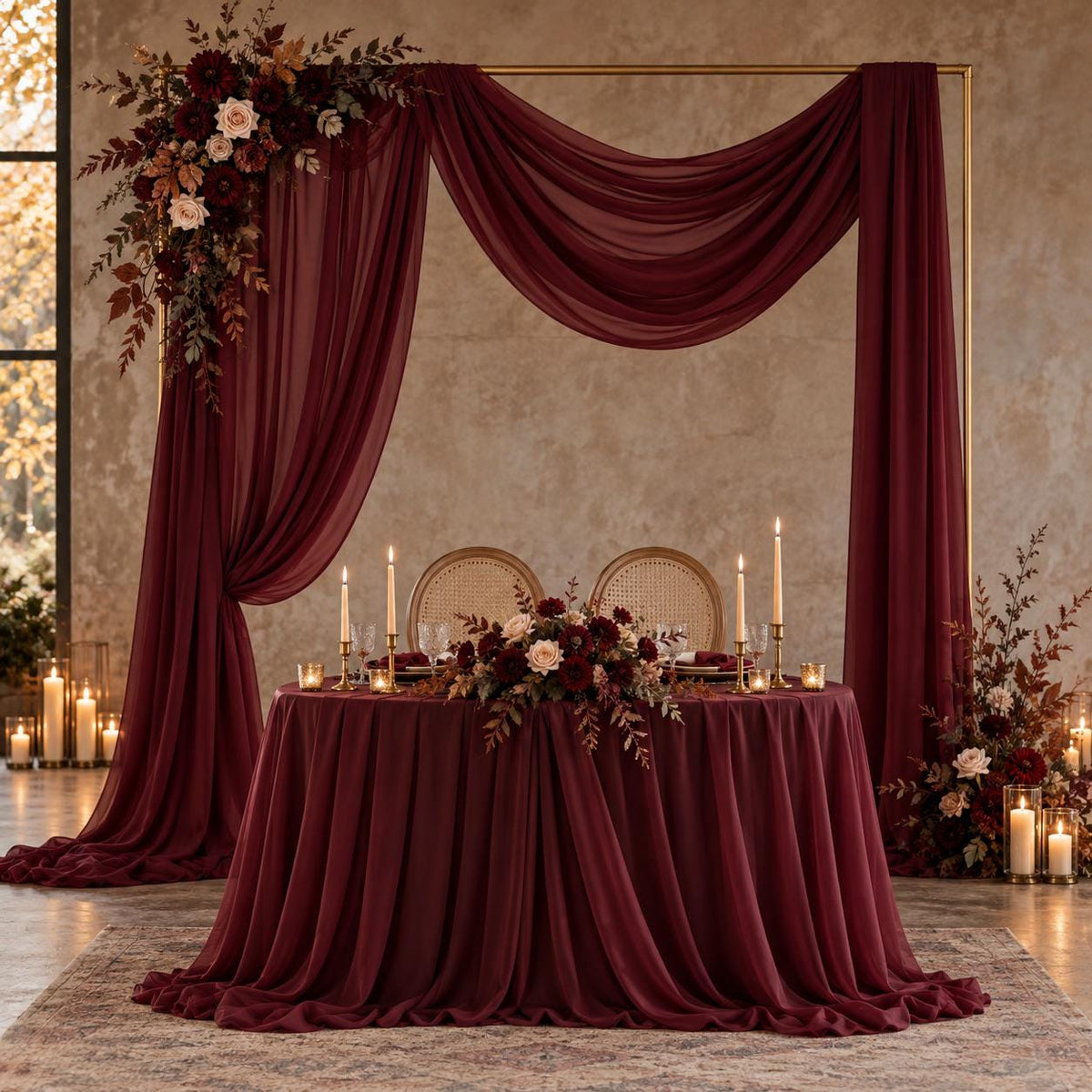 a beautifully decorated wedding reception table with a red tablecloth, floral centerpieces, and candles. The table is set for a formal event, with a large floral arch and a draped curtain framing the table. The overall setting has a romantic and elegant atmosphere.