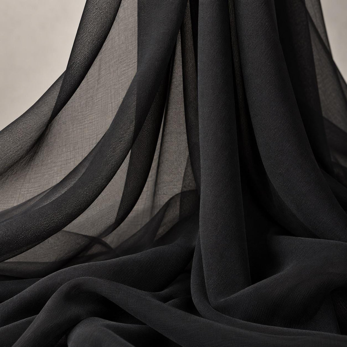 a close-up view of a black fabric, possibly silk or chiffon, with a smooth and flowing texture. The fabric appears to be made of a soft, shiny material and is draped or swirled in a way that creates a sense of movement and depth. The image does not contain any discernible text or countable objects, and the focus is solely on the fabric's texture and appearance.