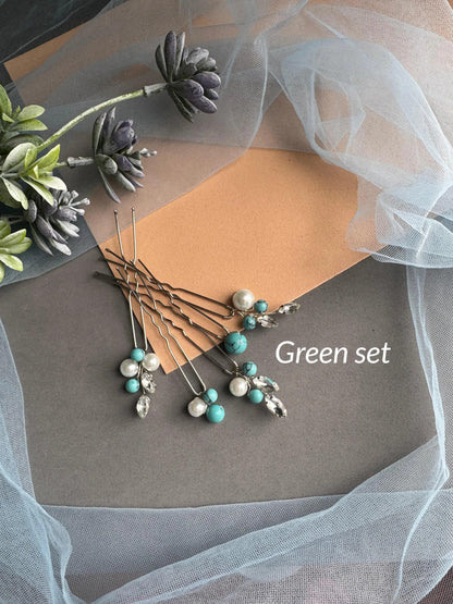 A collection of hair clips and beads arranged on a gray surface, with a white tulle fabric and some purple flowers in the background.