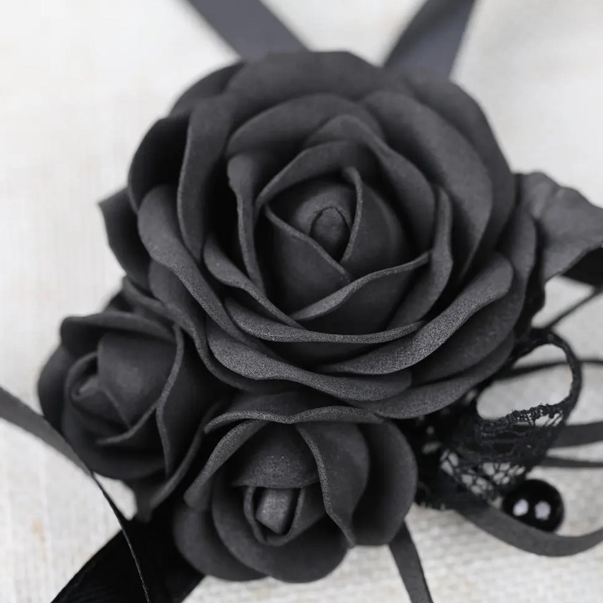 A close-up image of a black rose flower with a lace bow.