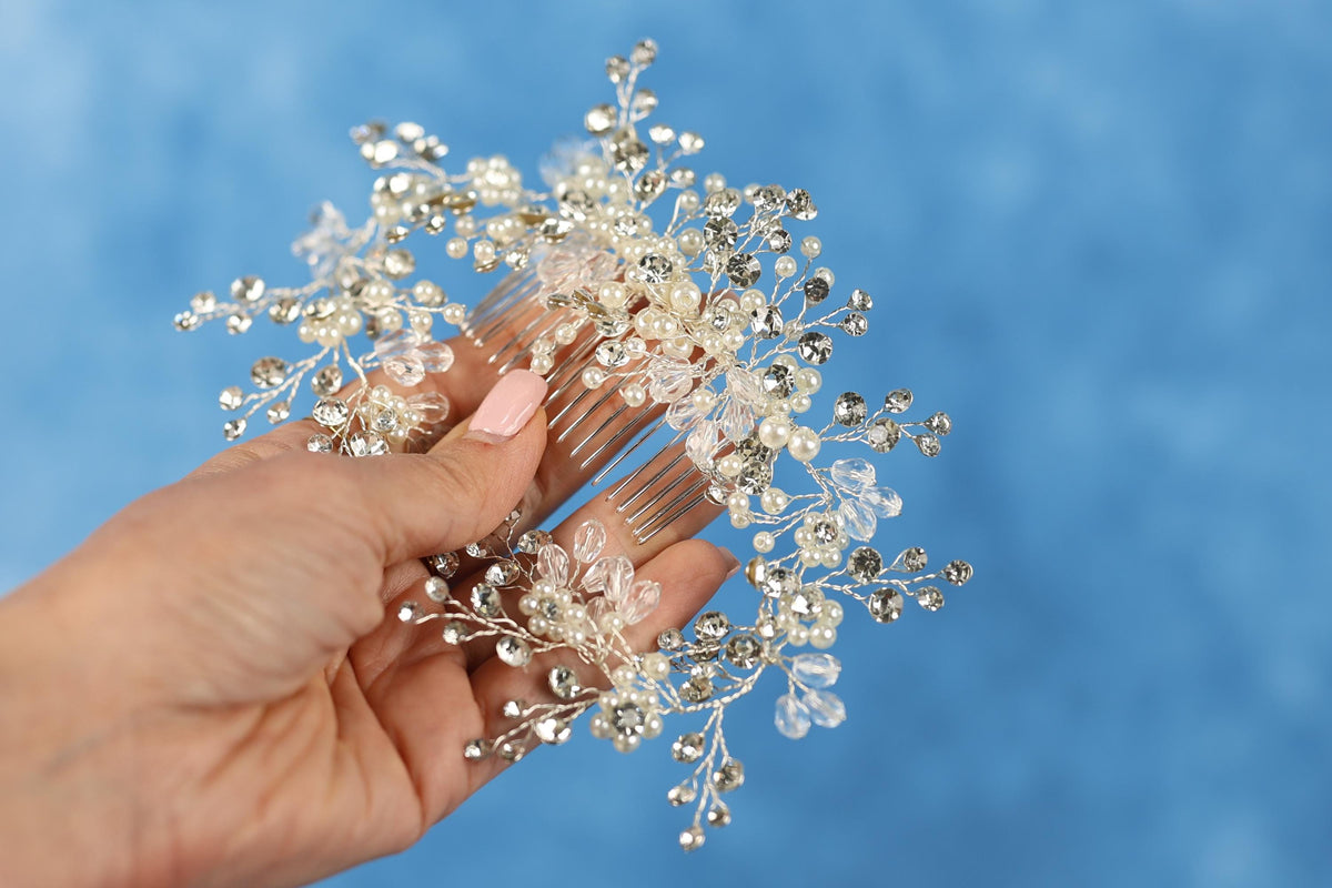 A hand holding a decorative hair accessory with a blue background.