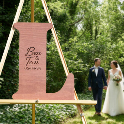 A wooden sign with the names "Ben & Tan" and the date "06/03/95" is displayed in the foreground, with a couple walking in the background.