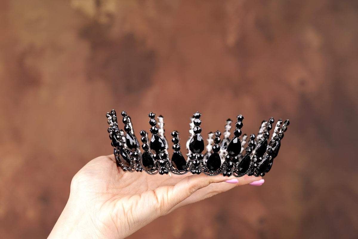 a hand holding a small black and white crown