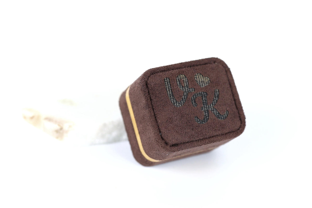 A brown, square-shaped jewelry box with the word "L" and a heart symbol printed on it.