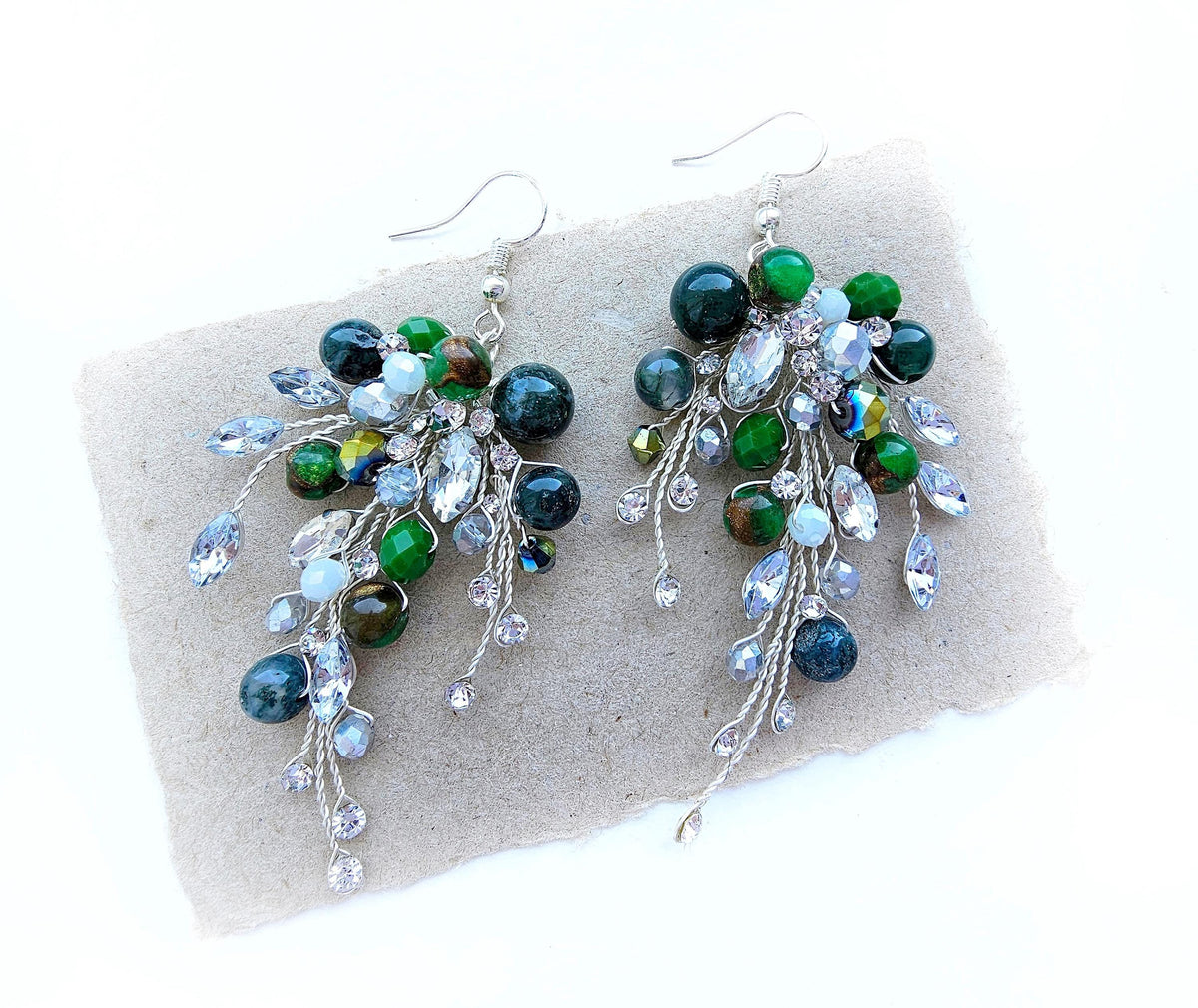 a pair of green and white earrings sitting on top of a piece of paper