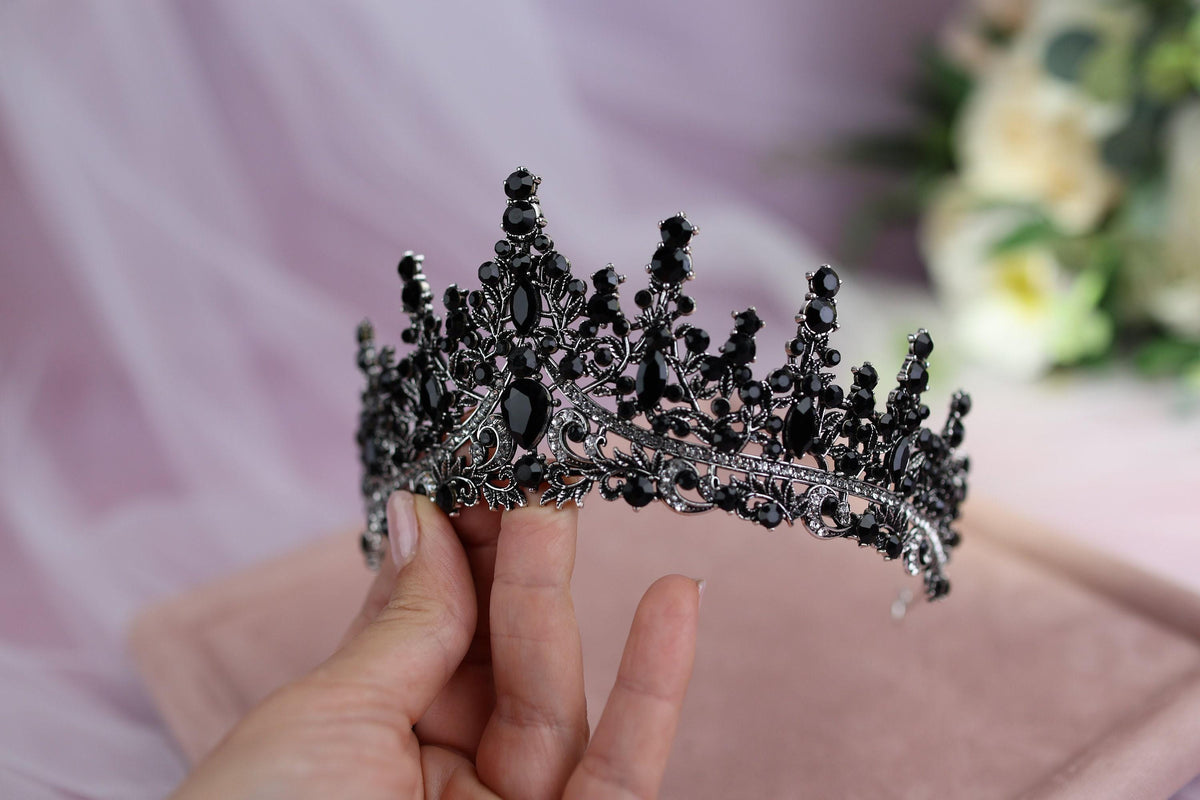 a hand holding a tiara in front of a bouquet