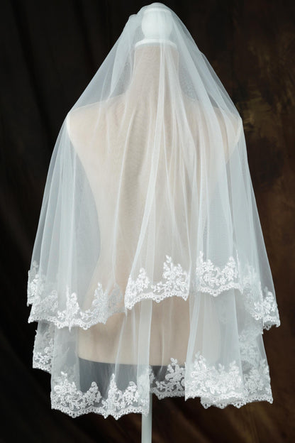 A mannequin wearing a white wedding veil with delicate lace trim.