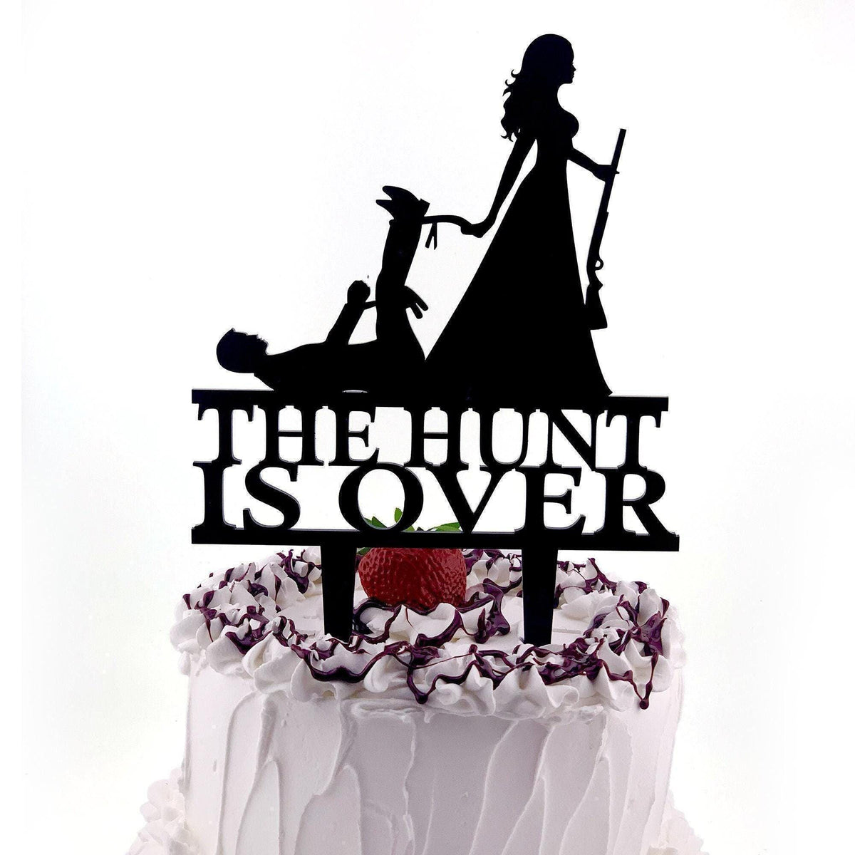 a cake with a silhouette of a woman holding a rifle and the text "THE HUNT IS OVER" on the cake topper.