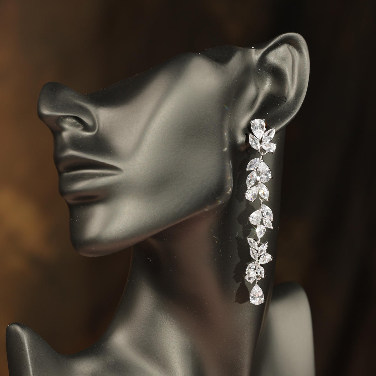 A close-up of a mannequin head wearing a pair of elegant diamond earrings.