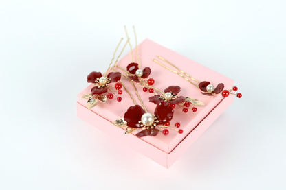 A pink box with red and gold floral decorations, including flowers and berries, placed on a white background.