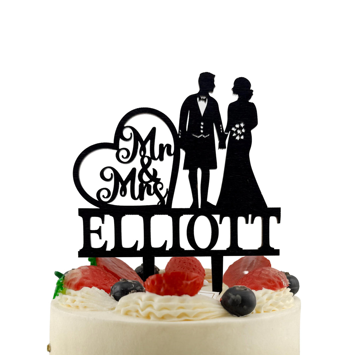 A black silhouette of a bride and groom on a wedding cake topper, with the name "Ellott" written below them.