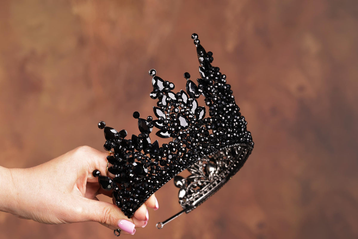 a woman's hand holding a black tiara