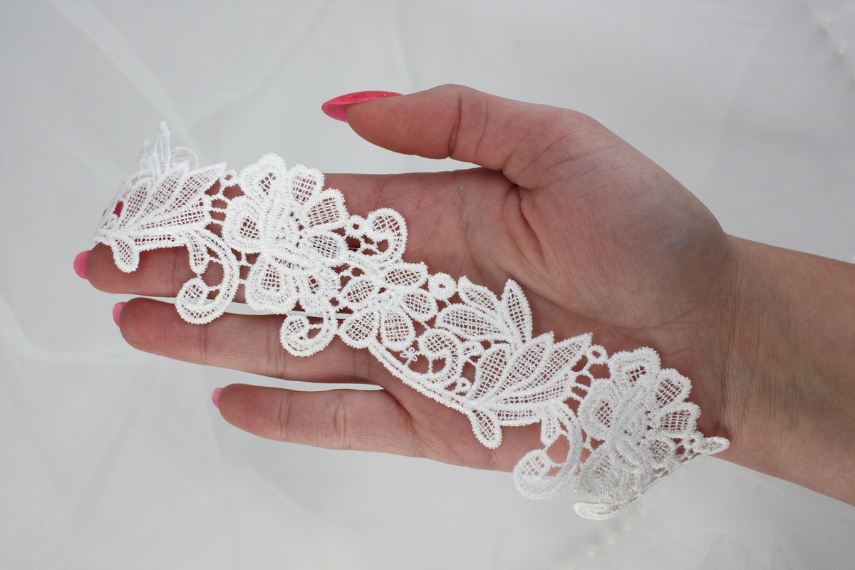 a woman's hand holding a piece of white lace