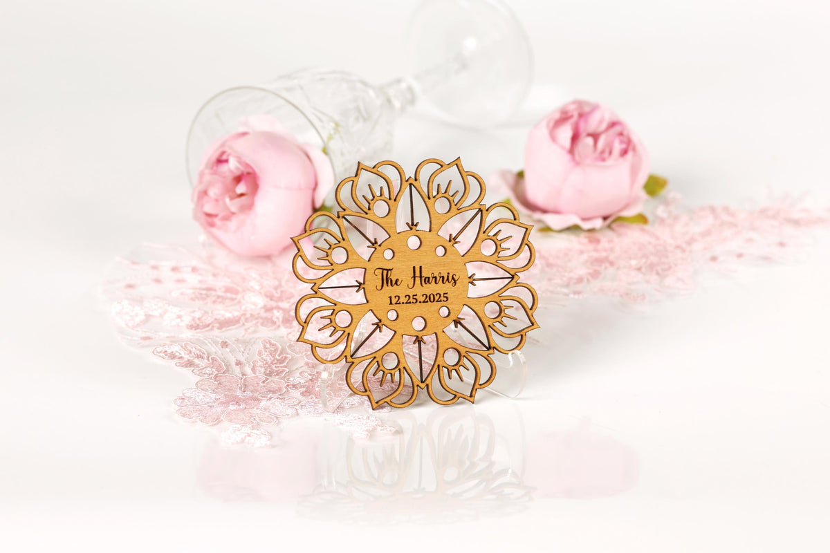 a wooden ornament with a floral design, placed on a white surface alongside two pink roses and a glass of wine.