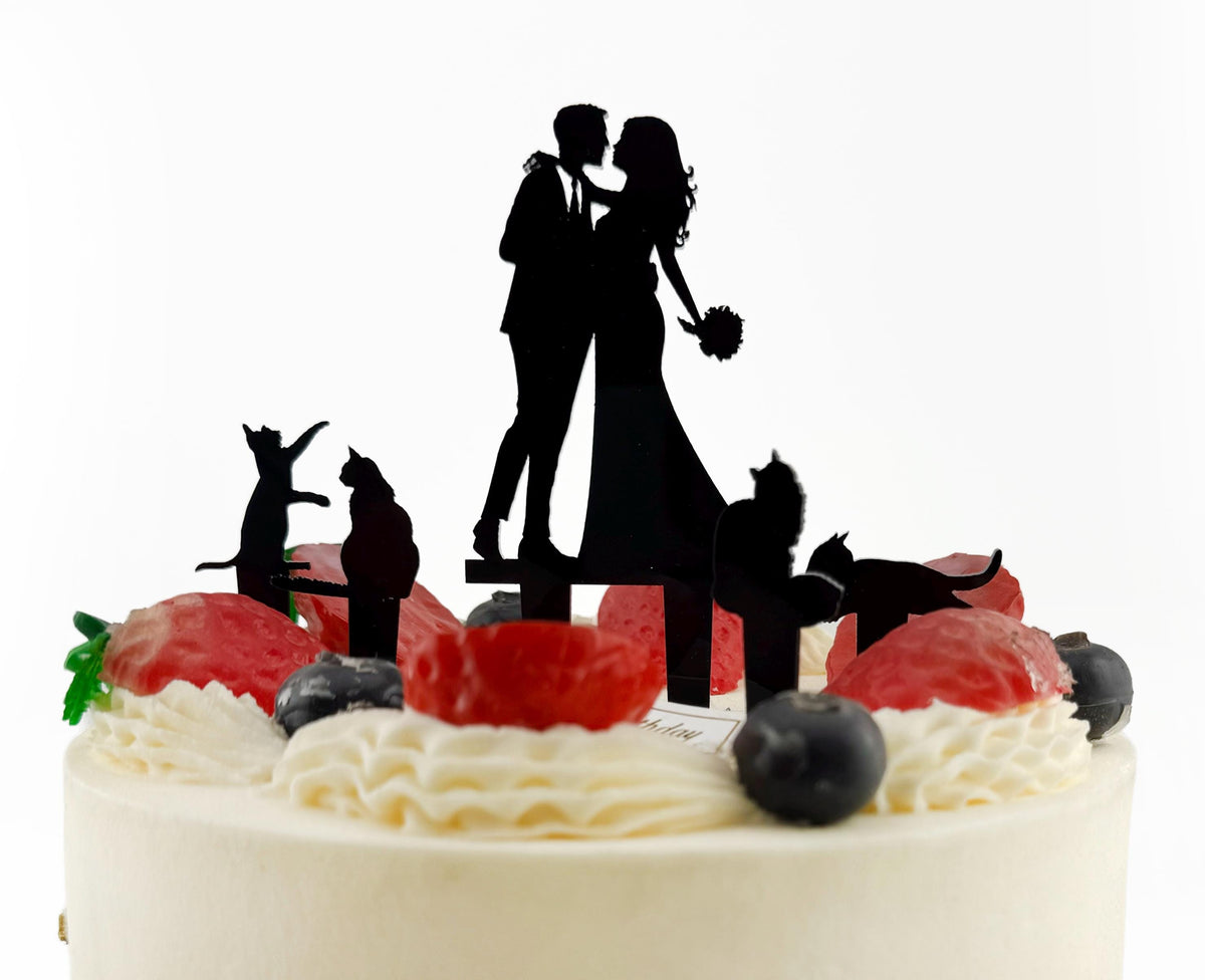 A silhouette of a bride and groom on top of a cake, surrounded by various fruit and decorative elements.