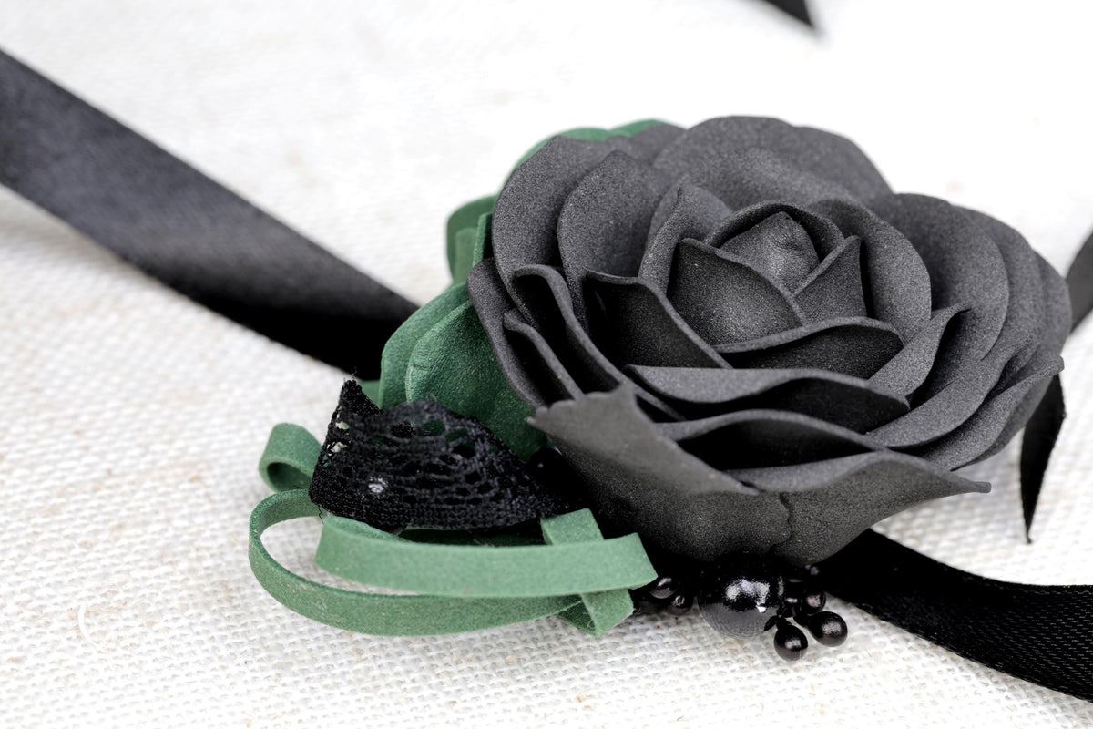 a black rose with a green ribbon on a white cloth