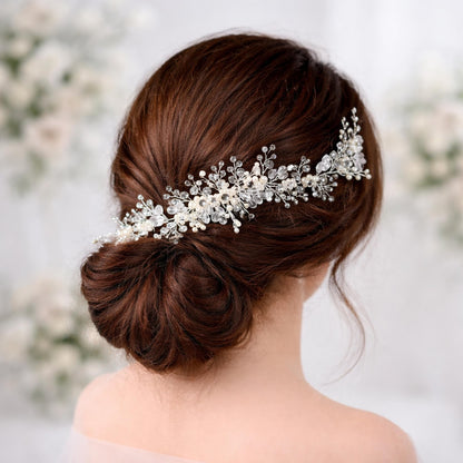 the back view of a woman's head with her hair styled in a bun, adorned with a decorative hair accessory featuring small white flowers and crystals.
