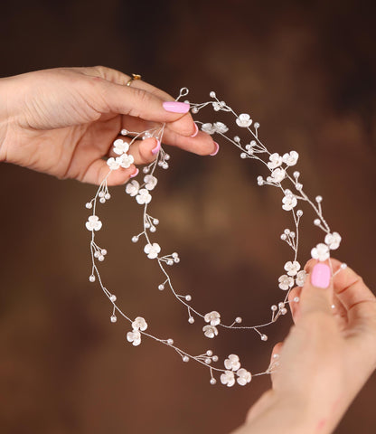 a woman is holding a white flower headpiece