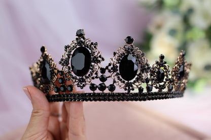 a woman holding a tiara with black stones on it