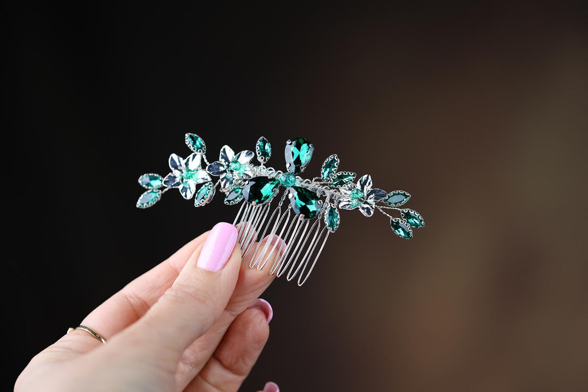 a woman's hand holding a hair comb with green leaves on it