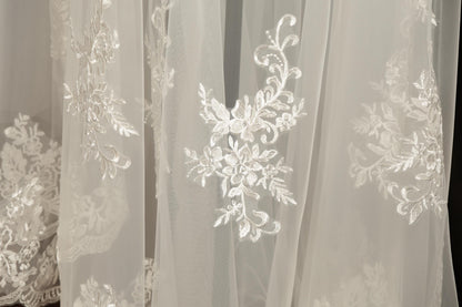 a close-up view of delicate white lace fabric with intricate floral embroidery.