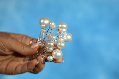 A hand holding a cluster of white pearls against a blue background.