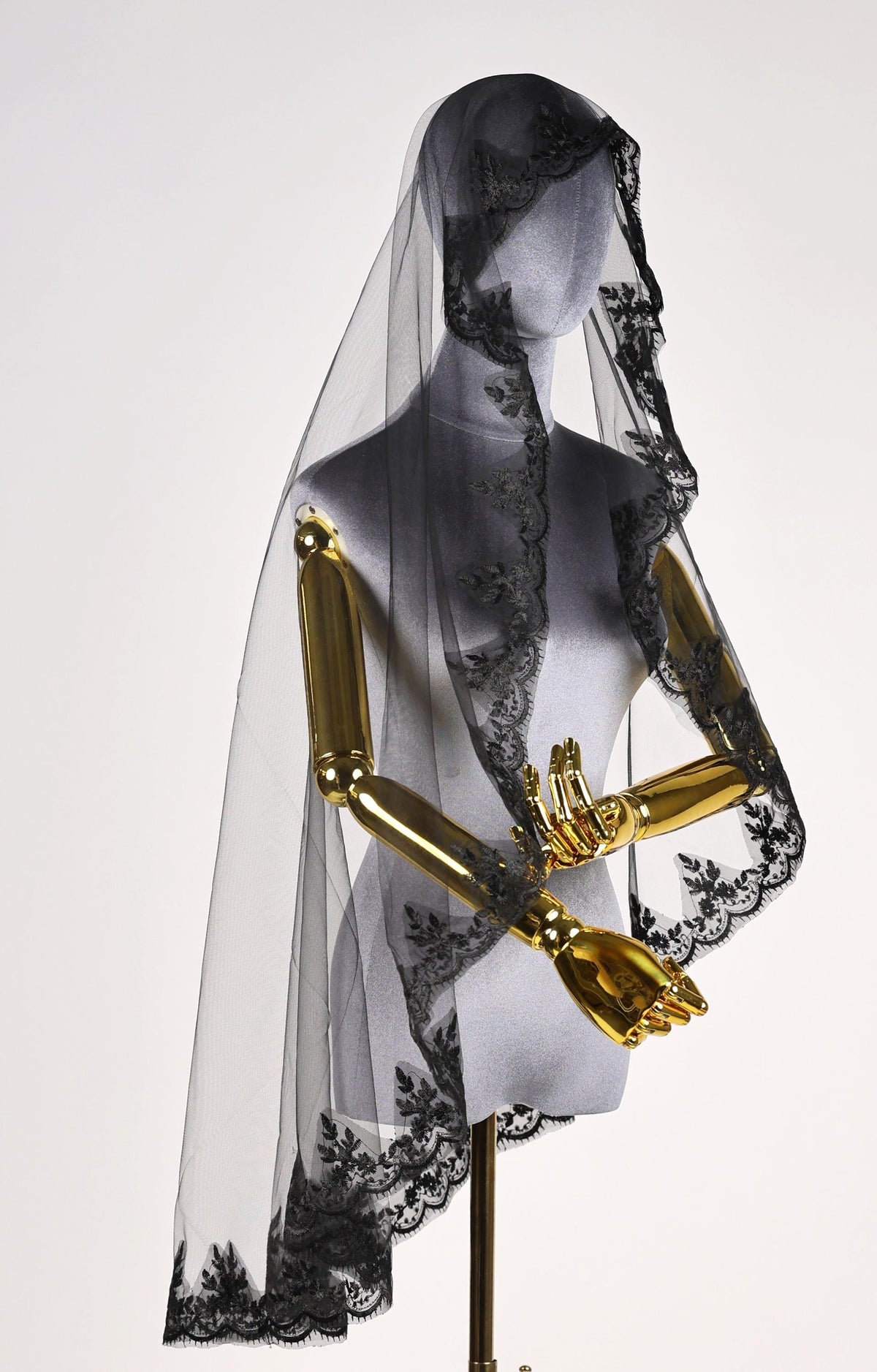 A mannequin wearing a black lace veil with a delicate floral pattern.