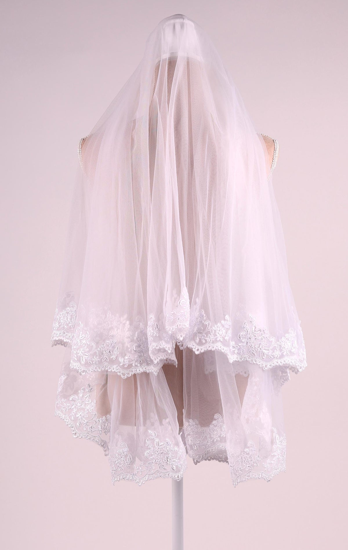 A white wedding veil with lace trim, displayed on a mannequin.