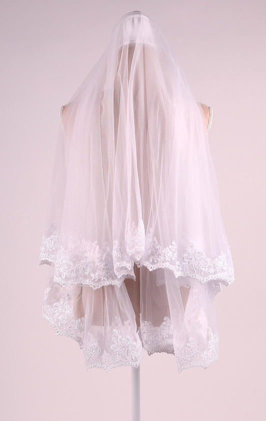 A white wedding veil with lace trim, displayed on a mannequin.