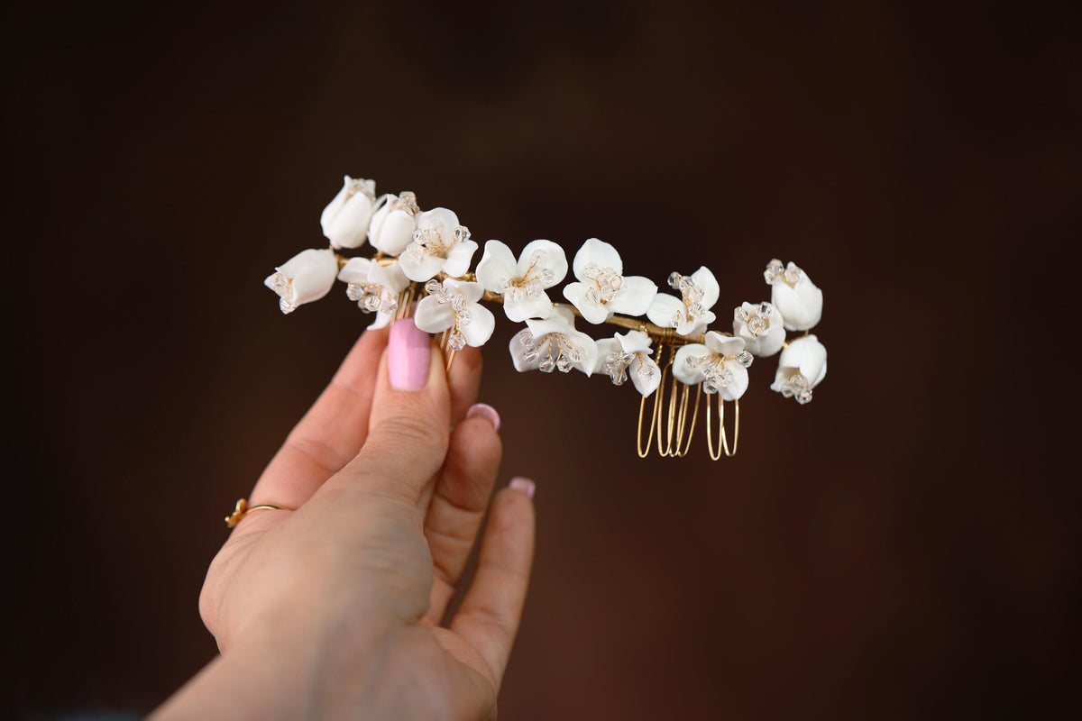 a hand holding a comb with white flowers on it