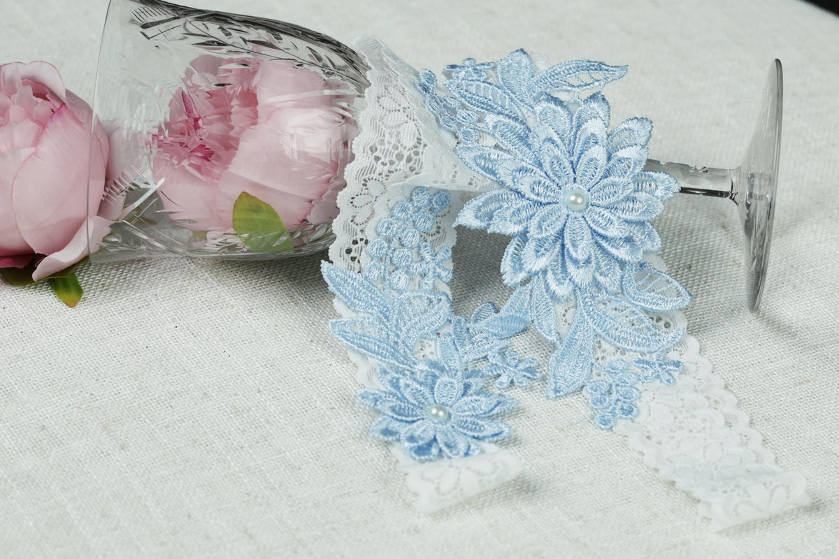 a clear glass vase with a pink flower inside, along with a lace flower accessory and a white lace ribbon.