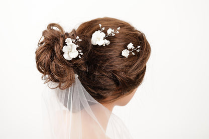 A close-up of a woman's hair with a bun and delicate white flower decorations.