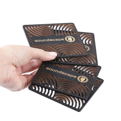 A hand is holding a stack of three black business cards with a repeating pattern of brown and white waves.