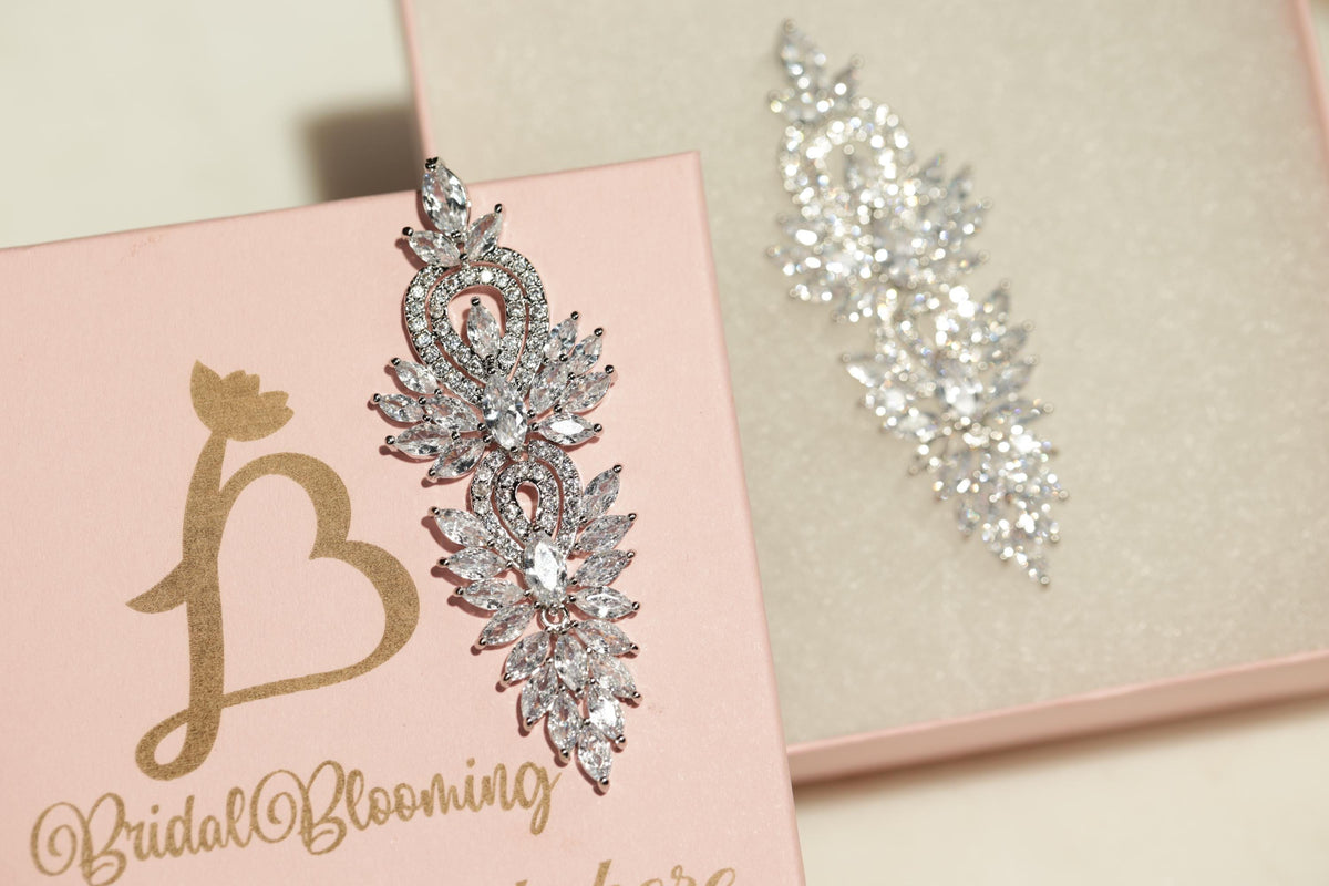 a pink box with a gold letter "B" and a large, sparkling crystal earring attached to it.
