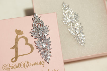 a pink box with a gold letter "B" and a large, sparkling crystal earring attached to it.