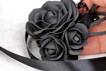 a hand holding a black ribbon and a flower