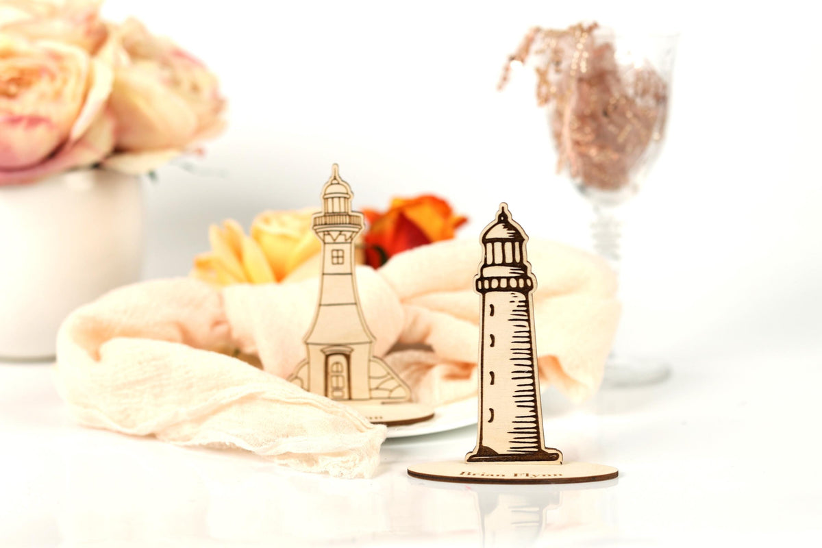 a wooden lighthouse and a vase of flowers on a table, with a glass of water and a pink rose in the background.