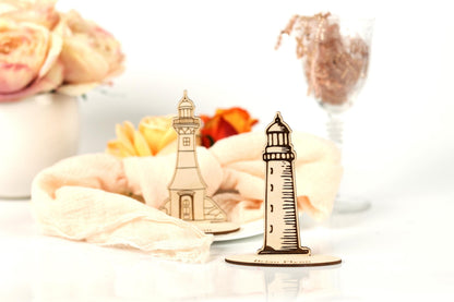 a wooden lighthouse and a vase of flowers on a table, with a glass of water and a pink rose in the background.
