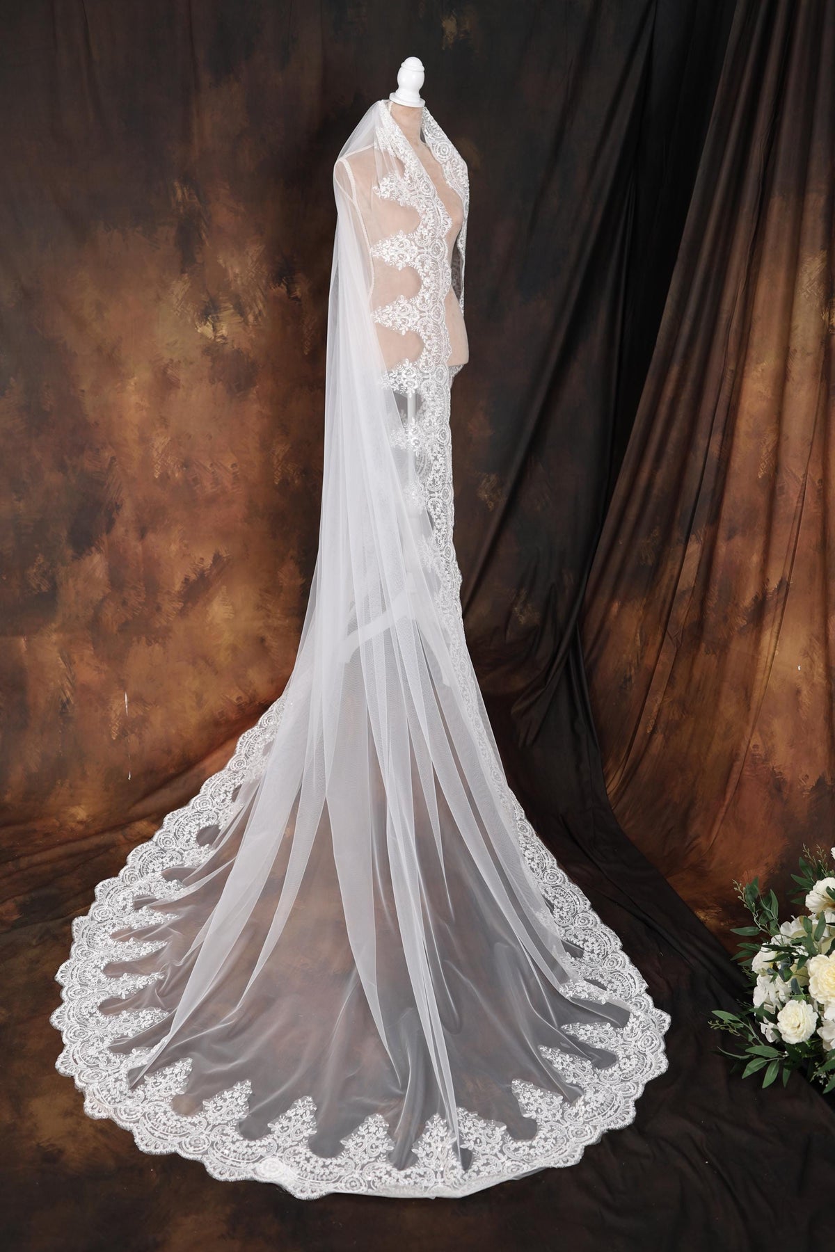 a wedding veil on a mannequin next to a bouquet of flowers